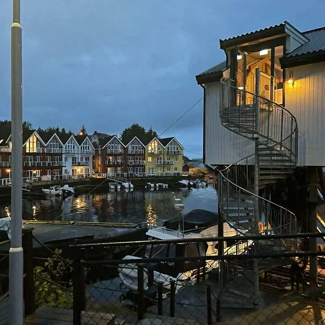 Kveldslys over brygge med rorbuer og spiraltrapp på sjøhus