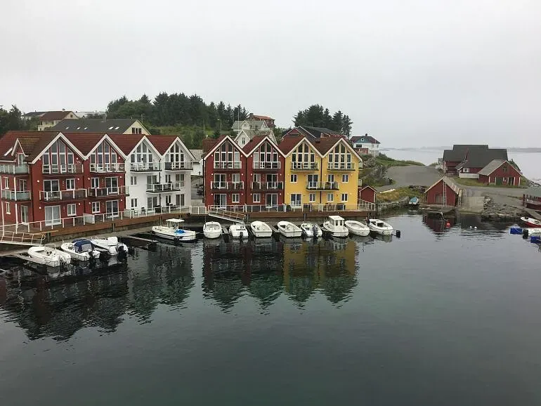 Fargerike rorbuer med båter fortøyd langs brygga